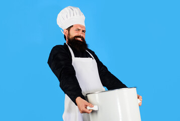 Male chef carrying heavy big pot at restaurant kitchen. Cooking and culinary. Bearded cook prepares...
