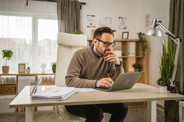 One adult man sit at office and look, read document on laptop at office