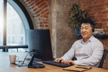 A man in a comfortable headset works in a stylish office with exposed brick walls and a modern...