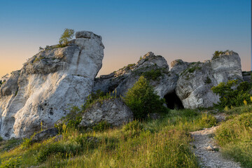 Fototapeta premium Limestone rock formations and cave entrance in summer landscape at sunset, Poland