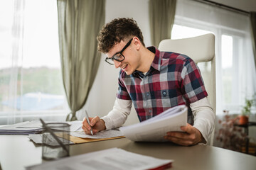 Young caucasian man sit and solve the questionnaire for school at home