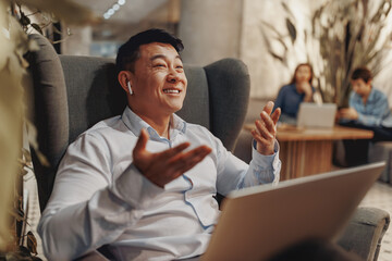 A man is enjoying a virtual meeting in his cozy workspace, showcasing how modern communication is...