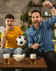 Young and adult man friends watch football match and cheer at home