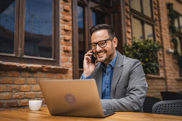 Adult man sit in a restaurant drink coffee and talk on mobile phone