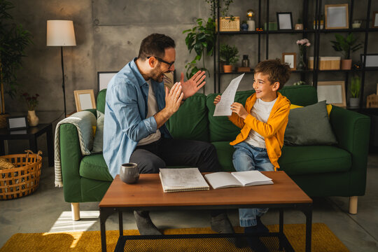 Happy and satisfied little boy show his father good grade on his test