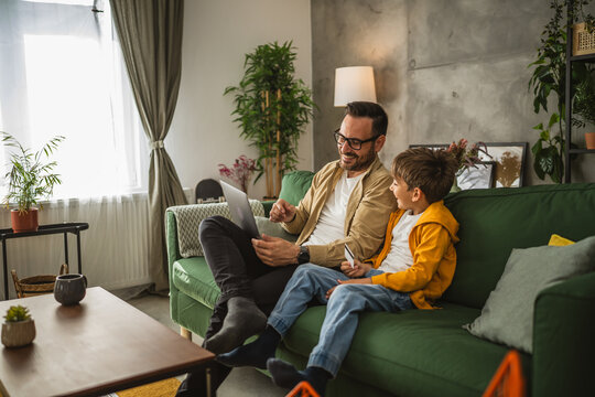 Father and son buy online with credit card on laptop at home