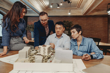 In a modern office environment, professionals are collaborating over a detailed architectural model...