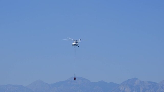 A firefighting helicopter carrying water to extinguish a forest fire