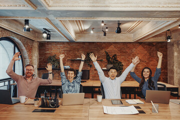 A joyful, enthusiastic team comes together to celebrate their success in a modern office...
