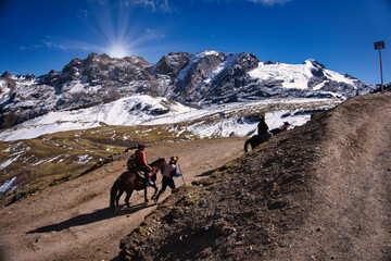 A stunning scene of a horse and rider with the majestic Vinicunca mountains in the background