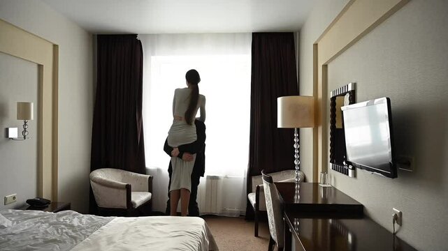 Young Caucasian couple hugging while standing by the window. - Powered by Adobe