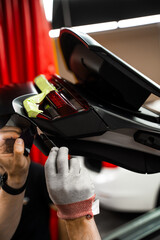 Technician trims car wrap using sharp razor blade ensures accurate vinyl wrap cutting. Precision...