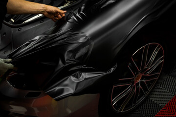 Car wrapping process using black matte vinyl stretched into place. Careful application and...