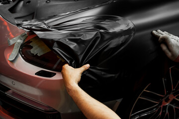 Matte black vinyl wrap application on front fender and wheel arch of luxury vehicle. Vinyl Wrapping...