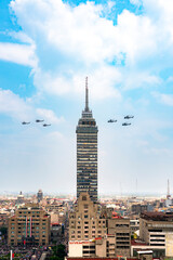 Obraz premium Military aircraft flying past Torre Latinoamericana during Independence Day parade on September 16 in Mexico City skyline