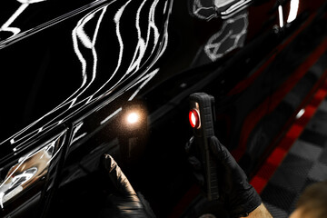 Swirl finder light to detect paint issues on black car in a detailing studio. Car Paint Inspection....