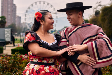 Portrait of a smiling young couple, dressed as Chilean huasos, looking at each other and posing...
