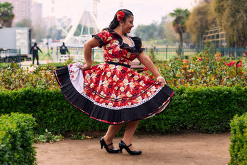 Portrait of a beautiful, smiling young woman, happily dressed in a Chilean huasa, celebrating,...