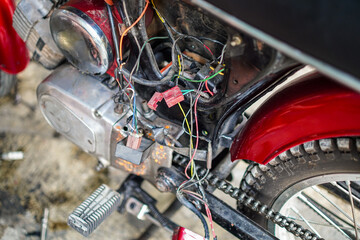 A detailed close-up reveals the inner workings of a vintage motorcycle, showcasing its complex wiring and mechanical components. The red accents add a pop of color against the silver and black.