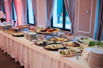 Lavish buffet table with salads fruit and pastries set up in an elegant room for a special event or celebration