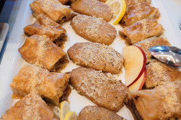 Layers of flaky phyllo dough walnut fillings drizzled with syrup and sprinkled with nuts served on white plate