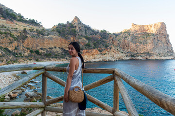 MUJER JOVEN MORENA MIRANDO AL MAR DESDE playa paradisíaca cala del moraig turismo españa verano 2025  Cala del Moraig, a paradise beach, is a Spanish tourist destination, summer 2025
