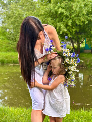 Mother and daughter with a Kupala wreath on the shore of the lake