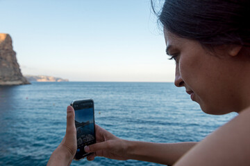 mujer sacando fotos con el teléfono en la playa paradisíaca cala del moraig turismo españa...