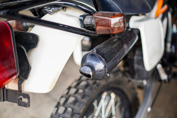 A close-up capturing the exhaust pipe and rear details of a sturdy motorcycle, showcasing its design and functionality. The image emphasizes mechanical elements and robust construction.