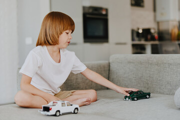 Young boy playing with toy cars in a cozy living room, expressing joy and creativity while enjoying...