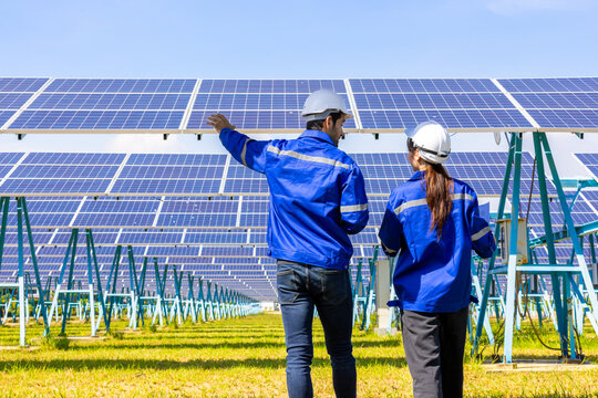 Architects and engineer team woman and man working on solar panel and blueprints with Solar photovoltaic equipment on factory construction site. meeting, planing, brainstorming. Factory worker. 