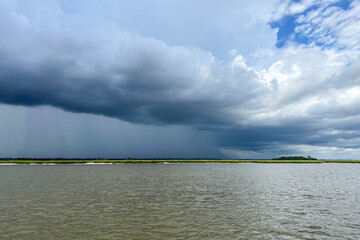 A line of clouds and a storm behind them as viewed from the water on the intracoastal waterway