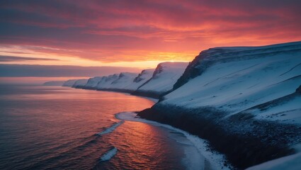Snow-covered cliffs along a coastline at sunset with vibrant sky colors.