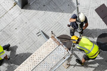 Two construction workers assembling european scaffolding