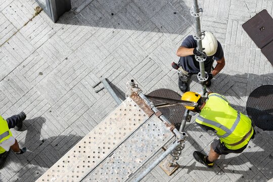 Two construction workers assembling european scaffolding