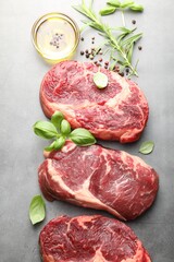 Pieces of raw beef meat and spices on grey table, flat lay