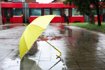 Yellow umbrella on wet asphalt outdoors, space for text