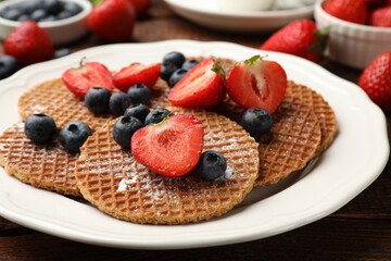 Tasty Dutch waffles (stroopwafels) and berries on wooden table, closeup