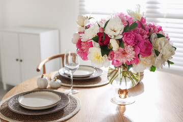 Beautiful table setting with bouquet of peonies in dining room, closeup