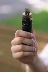 Young woman with electronic smoking device outdoors, closeup