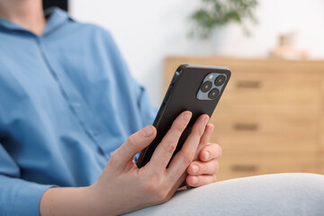Woman using modern smartphone at home, closeup