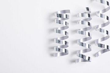 Shiny party streamers on white background, flat lay. Space for text