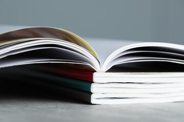 Stack of different magazines on grey table, closeup