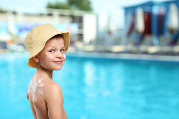 Little boy with sun protection product on his skin by outdoor swimming pool