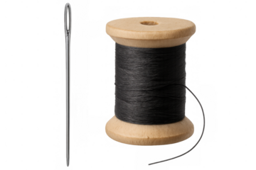 Sewing needle resting near wooden thread spool, black cotton thread positioned for textile crafting