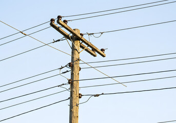 Wooden Power Pole with Electrical Wires, Infrastructure, Utility, Electricity Supply Against Blue Sky.