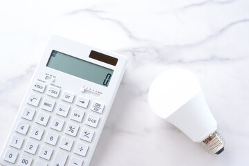 電卓と電球で、高騰する電気代のイメージ
