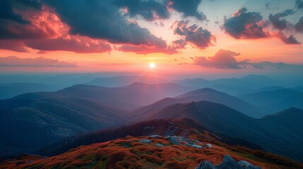 Mountain range under a vibrant sunset, pink and orange clouds, blue layers receding into the distance