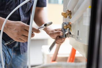HVAC Technician Using Wrench to Connect AC Pipes, Close-up of Hand Installing Refrigerant Lines on...