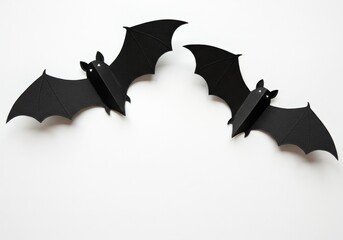 Two black paper bats are featured against a bright white backdrop, creating a festive Halloween scene.
